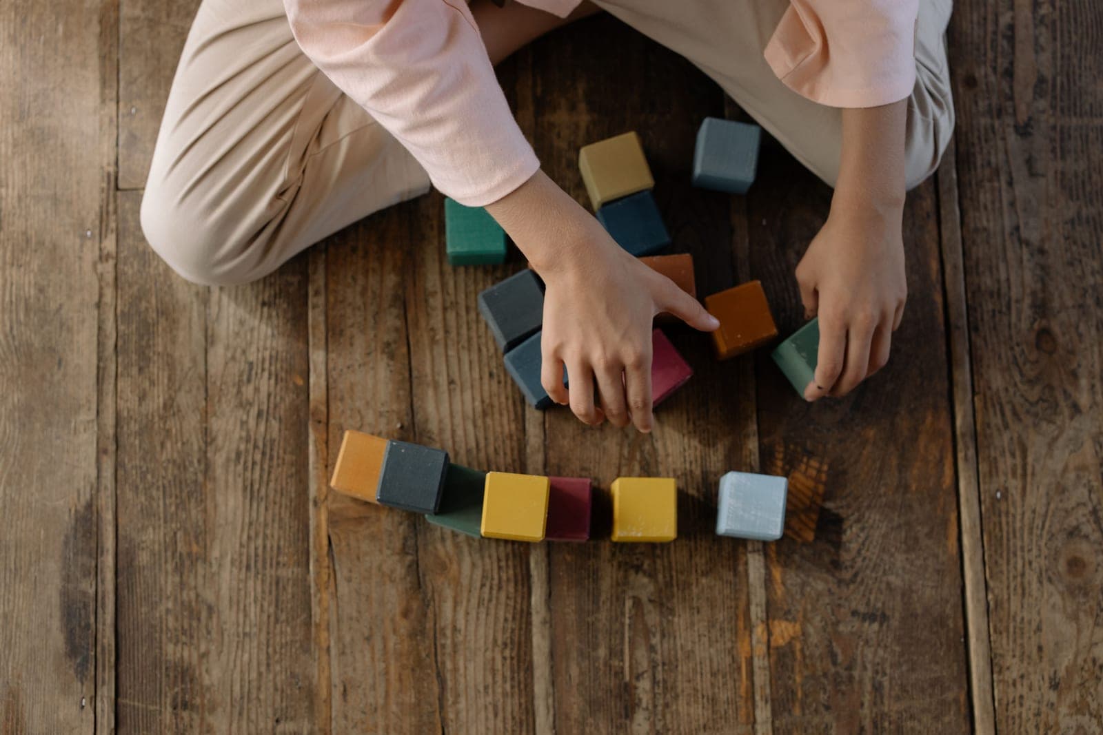 A child building a structure from colorful wooden blocks